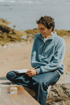 Patron de couture sweat homme Thomas avec col montant zippé, manches raglan et coupe confortable, porté en bord de mer